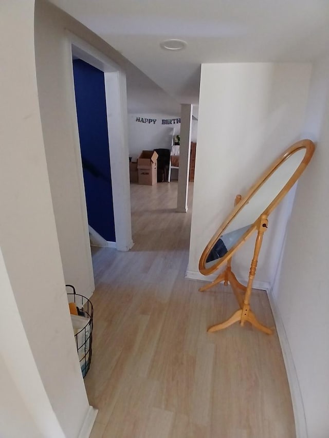 hall featuring wood finished floors and an upstairs landing