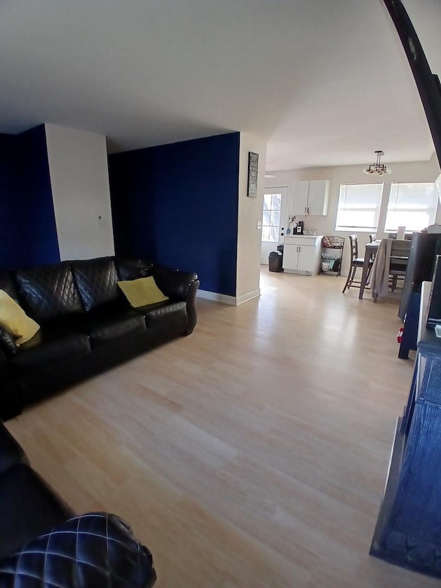 living area featuring light wood-type flooring, baseboards, and a chandelier