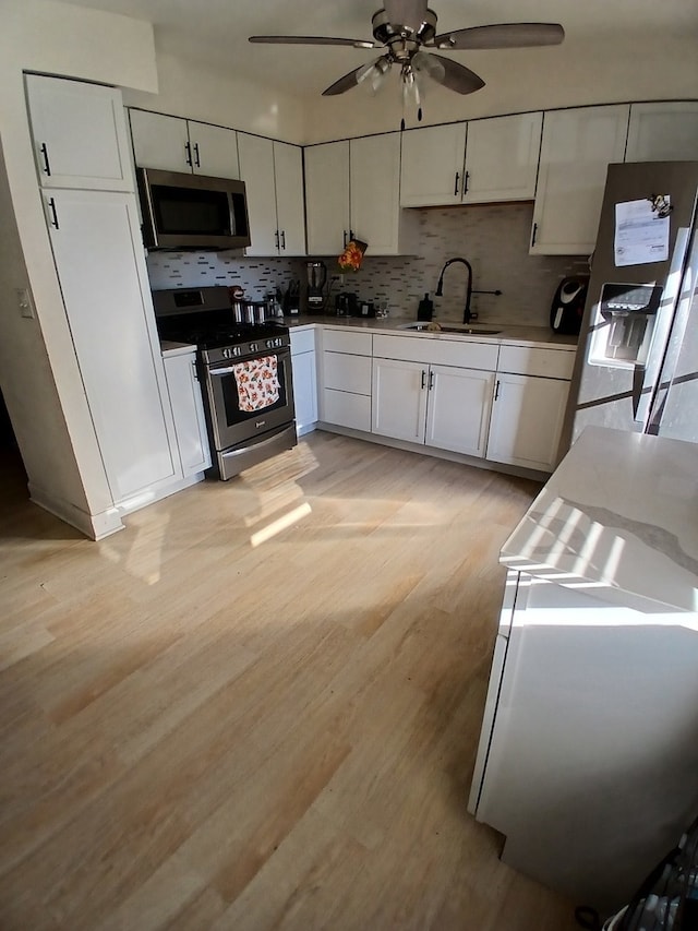 kitchen featuring white cabinets, light wood-type flooring, appliances with stainless steel finishes, and sink