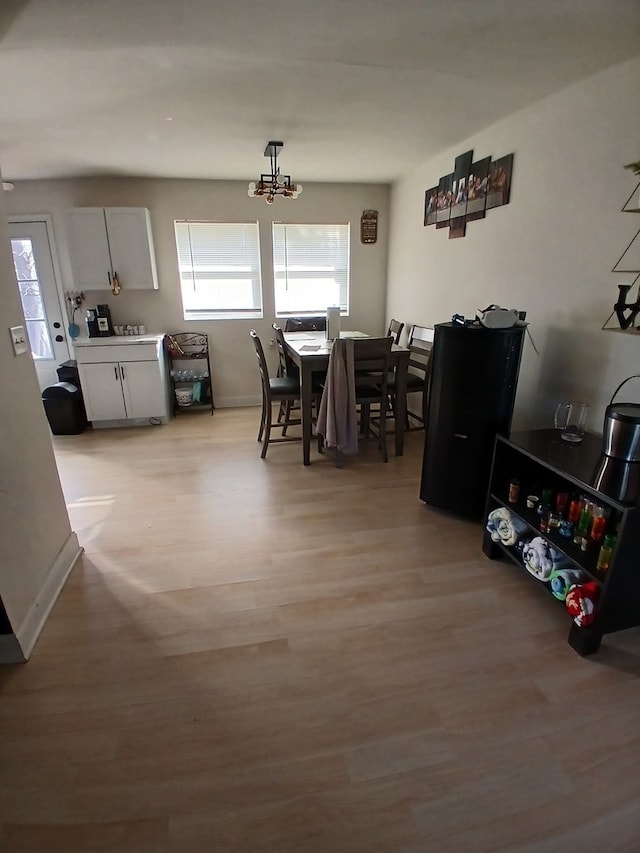 dining space with light wood-type flooring, washer / clothes dryer, and a notable chandelier