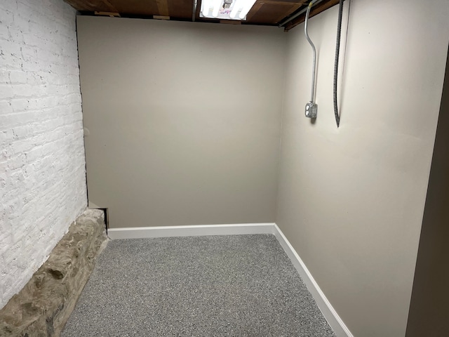 interior space featuring carpet flooring and brick wall