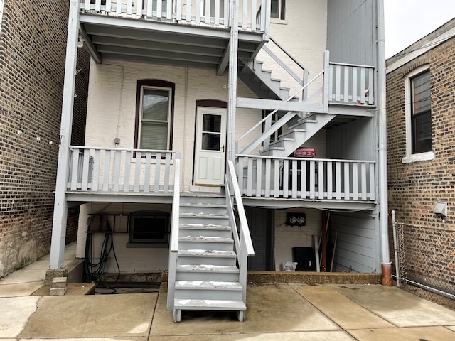 view of exterior entry featuring a patio and a balcony