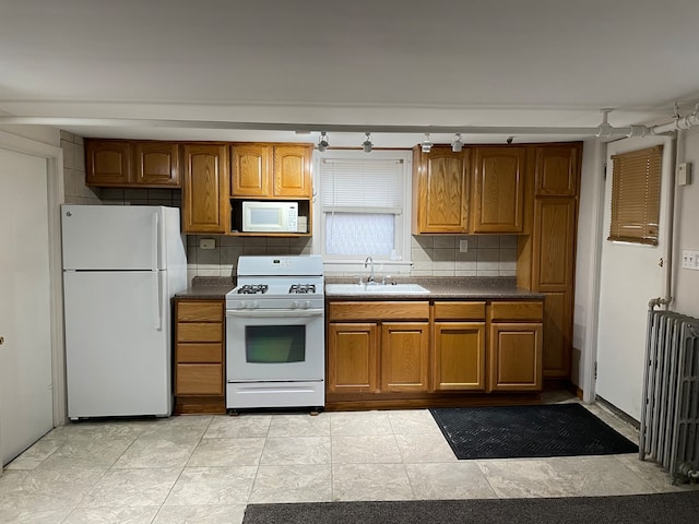 kitchen with sink, tasteful backsplash, light tile patterned floors, white appliances, and radiator heating unit