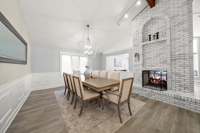 dining area featuring vaulted ceiling with beams, hardwood / wood-style flooring, rail lighting, and a notable chandelier