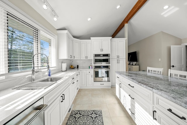 kitchen with white cabinetry, lofted ceiling with beams, light tile patterned flooring, and stainless steel appliances