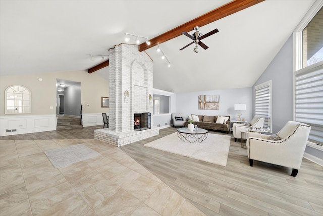 living room featuring a wealth of natural light, a fireplace, ceiling fan, and track lighting