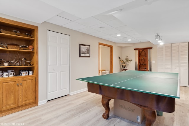 recreation room with light hardwood / wood-style flooring, a drop ceiling, and built in features