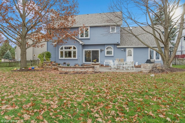 rear view of house with a patio area, a shingled roof, fence, and a lawn