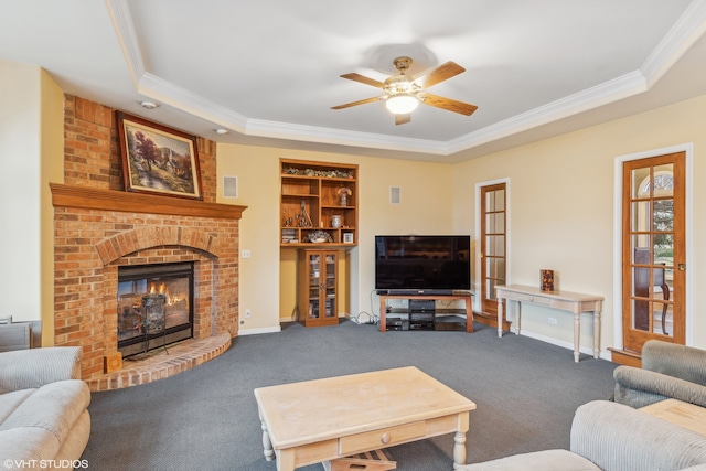 living area featuring baseboards, a tray ceiling, crown molding, carpet floors, and a fireplace