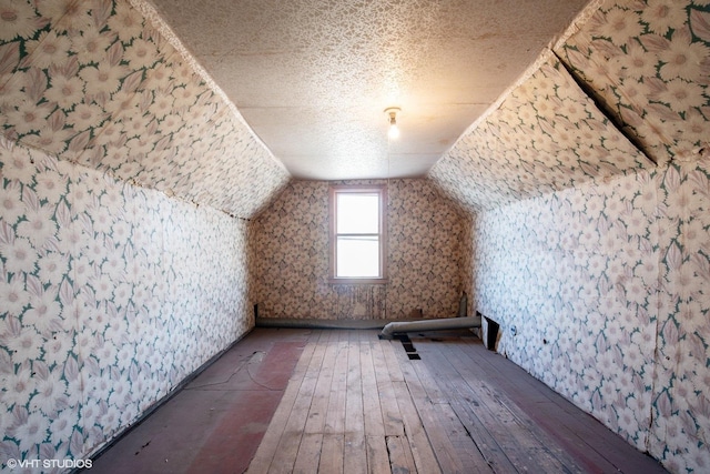 bonus room featuring wood-type flooring, lofted ceiling, and a textured ceiling