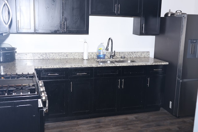 kitchen with black fridge, dark hardwood / wood-style floors, sink, and light stone counters