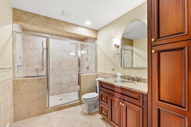 bathroom with tile patterned flooring, vanity, a shower with door, and tile walls