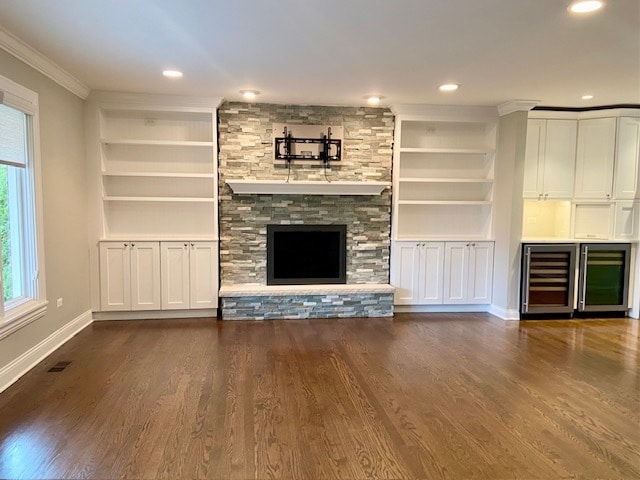 unfurnished living room with dark hardwood / wood-style floors, built in shelves, ornamental molding, a fireplace, and beverage cooler