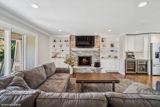 living room with hardwood / wood-style floors, built in shelves, a fireplace, and wine cooler