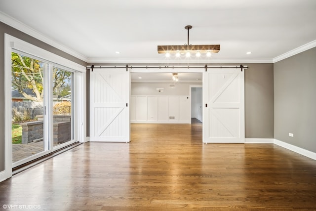 unfurnished dining area featuring hardwood / wood-style floors, a barn door, and ornamental molding