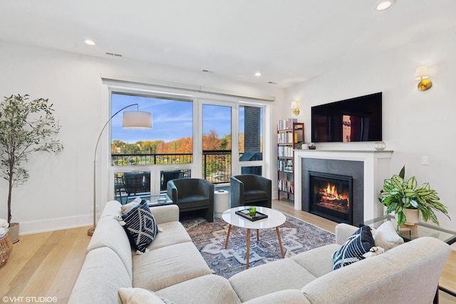 living room with a glass covered fireplace, recessed lighting, wood finished floors, and baseboards