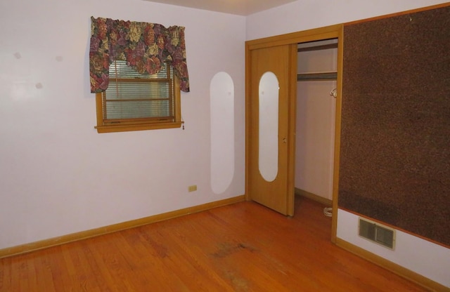 unfurnished bedroom featuring wood-type flooring and a closet