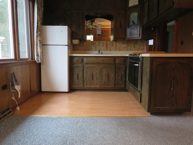 kitchen with white refrigerator, sink, ceiling fan, dark brown cabinets, and light hardwood / wood-style floors