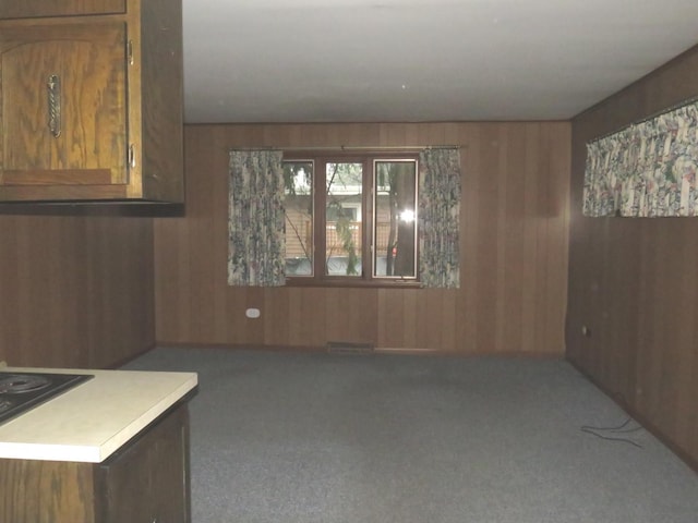 unfurnished dining area featuring carpet flooring and wooden walls