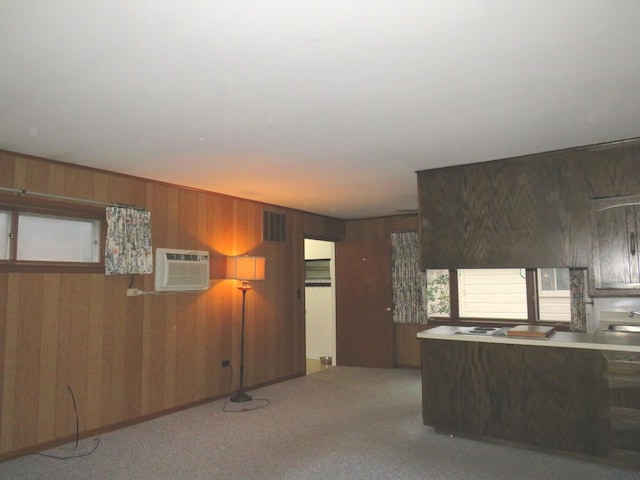 kitchen featuring an AC wall unit, wooden walls, sink, and light carpet