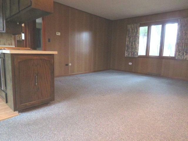 unfurnished living room with wooden walls and light carpet