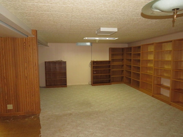 basement featuring wood walls, carpet floors, and a textured ceiling