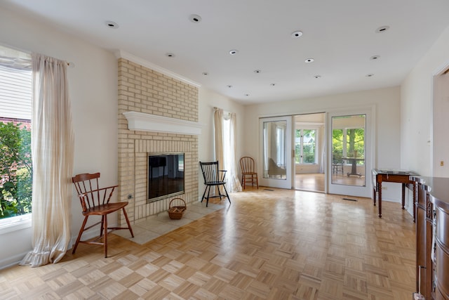 living area featuring a fireplace, a healthy amount of sunlight, and light parquet floors