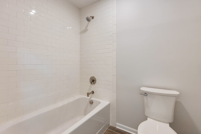 bathroom with toilet, tiled shower / bath, and wood-type flooring