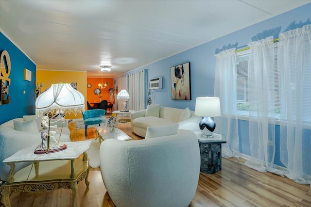 living room with an AC wall unit, light hardwood / wood-style flooring, and a notable chandelier