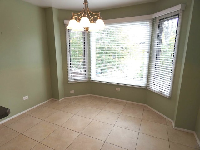 empty room featuring a wealth of natural light, a notable chandelier, and light tile patterned flooring