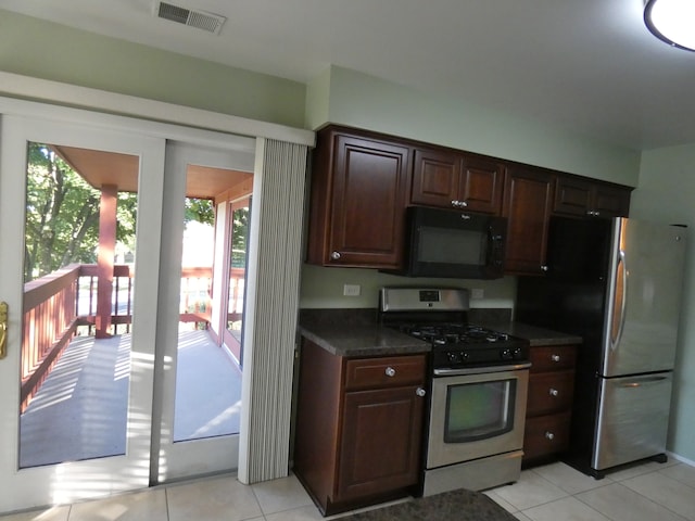 kitchen featuring a wealth of natural light, dark brown cabinets, light tile patterned floors, and appliances with stainless steel finishes