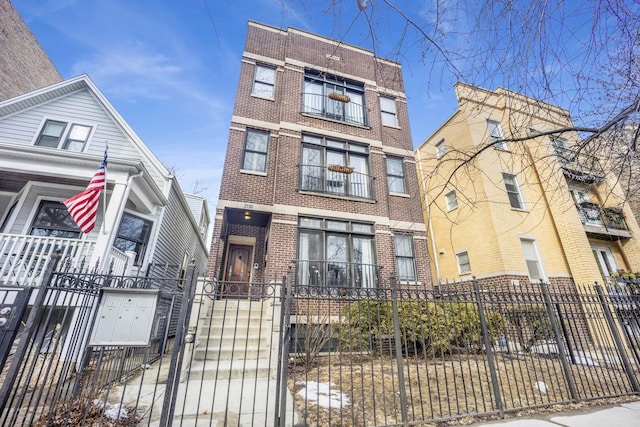 townhome / multi-family property featuring brick siding and a fenced front yard