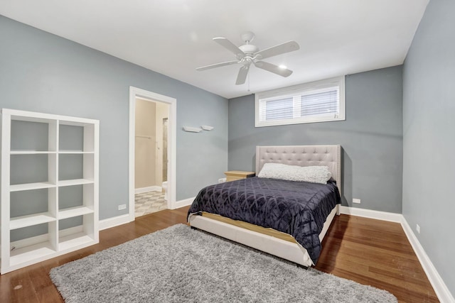 bedroom featuring ceiling fan, ensuite bath, baseboards, and wood finished floors