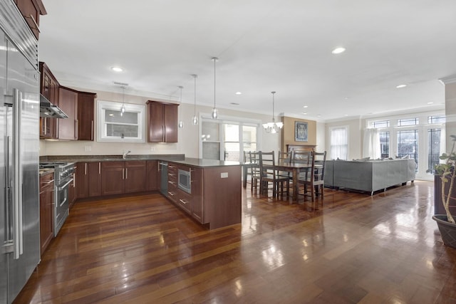 kitchen featuring dark countertops, a peninsula, appliances with stainless steel finishes, and open floor plan