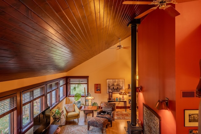 sitting room featuring lofted ceiling, wood ceiling, a wood stove, hardwood / wood-style floors, and ceiling fan