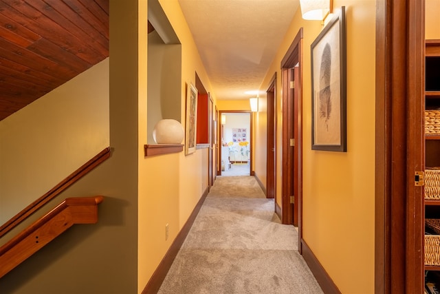 hall with light colored carpet and a textured ceiling