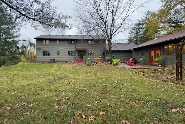 back of property with central air condition unit, a yard, and a patio area