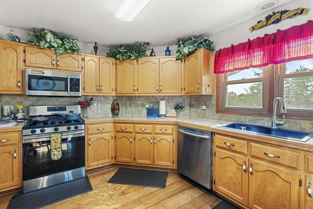 2708 Lake Shore Dr Unit 1, Joliet, IL 60431 - kitchen with appliances with stainless steel finishes, a sink, light wood-style floors, decorative backsplash, and tile countertops