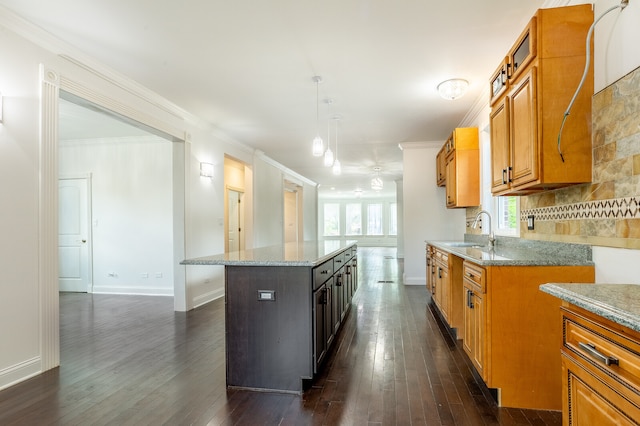 kitchen with dark hardwood / wood-style flooring, a center island, crown molding, light stone countertops, and decorative light fixtures