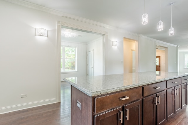 kitchen with light stone countertops, crown molding, a center island, pendant lighting, and dark hardwood / wood-style flooring