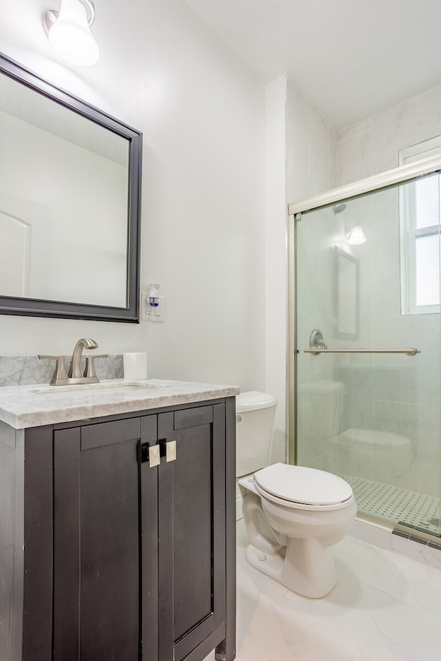 bathroom featuring toilet, vanity, and a shower with door