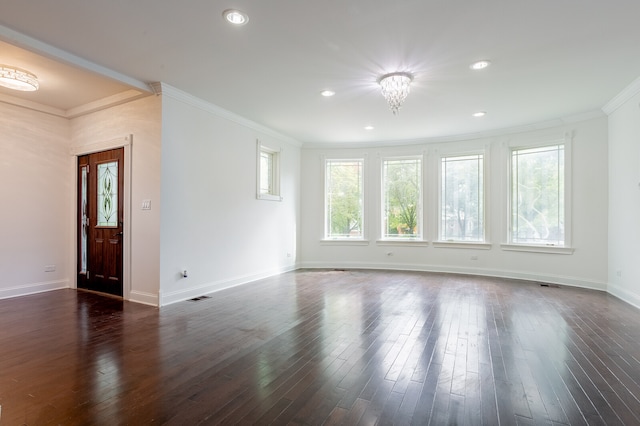 empty room featuring dark hardwood / wood-style flooring, a notable chandelier, and crown molding