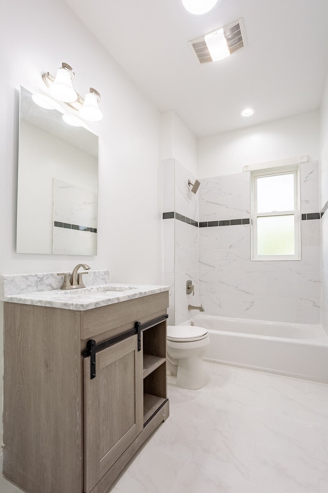 full bathroom featuring vanity, tiled shower / bath, and toilet