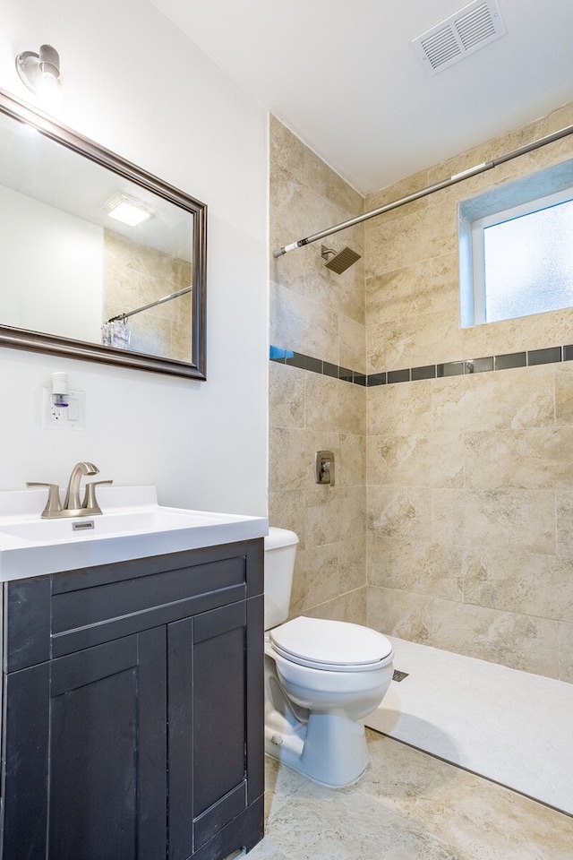 bathroom featuring toilet, vanity, and a tile shower