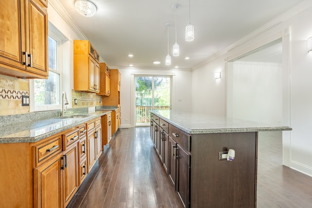 kitchen with dark hardwood / wood-style flooring, hanging light fixtures, sink, and a kitchen island