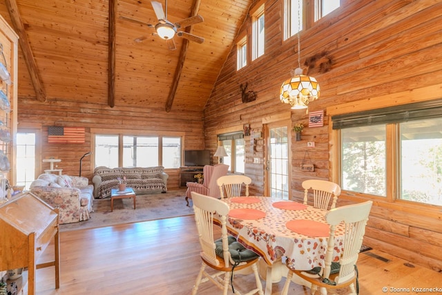 dining room with high vaulted ceiling, light wood-type flooring, a healthy amount of sunlight, and beam ceiling