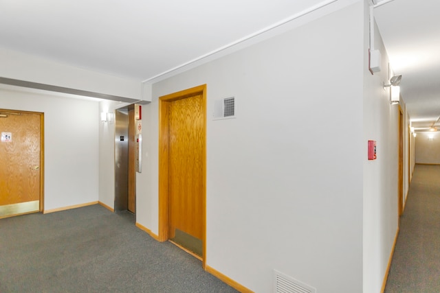 hallway with elevator and dark carpet