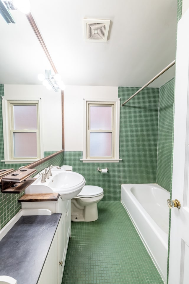 full bathroom featuring vanity, tile patterned floors, toilet, tile walls, and tiled shower / bath combo