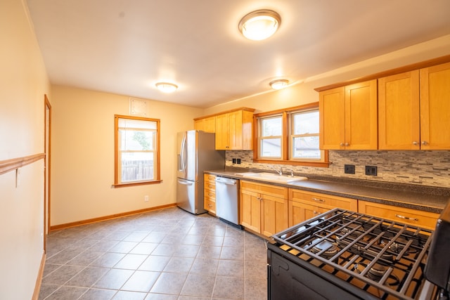 kitchen featuring appliances with stainless steel finishes, sink, tile patterned floors, and backsplash