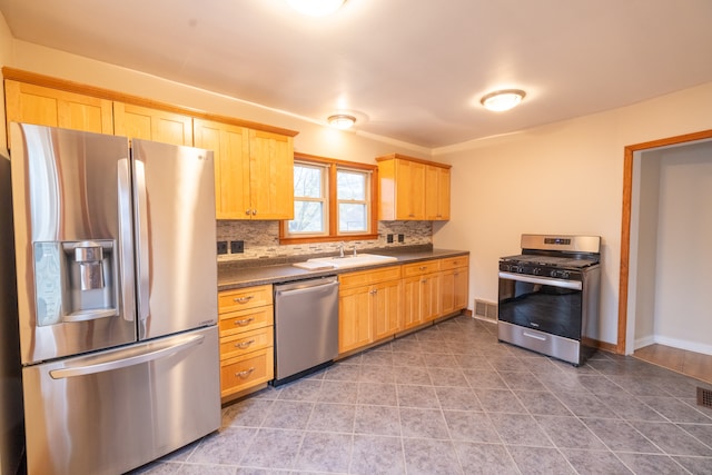 kitchen with stainless steel appliances, light brown cabinetry, sink, and tasteful backsplash